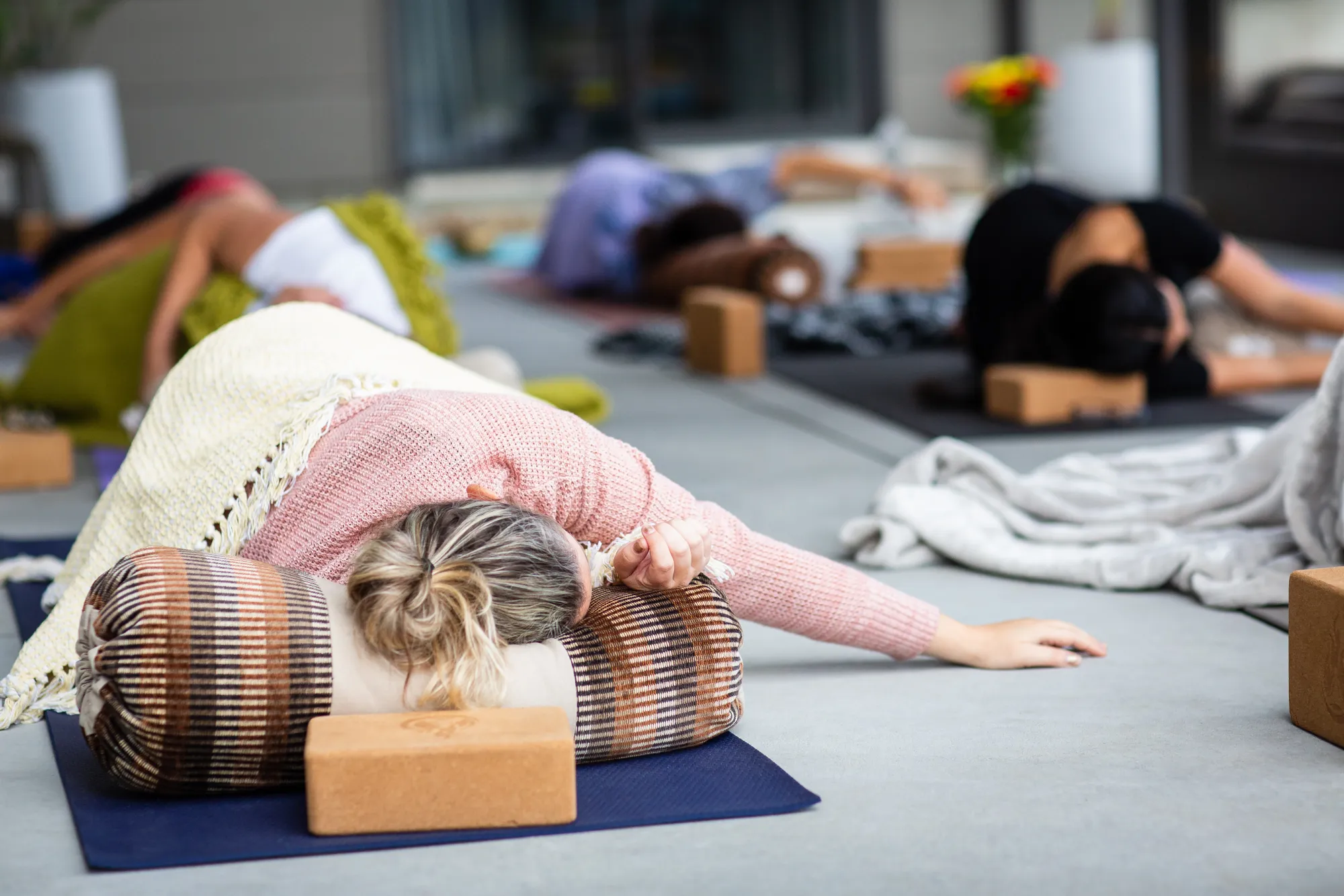 A participant resting in a supported restorative pose over a bolster