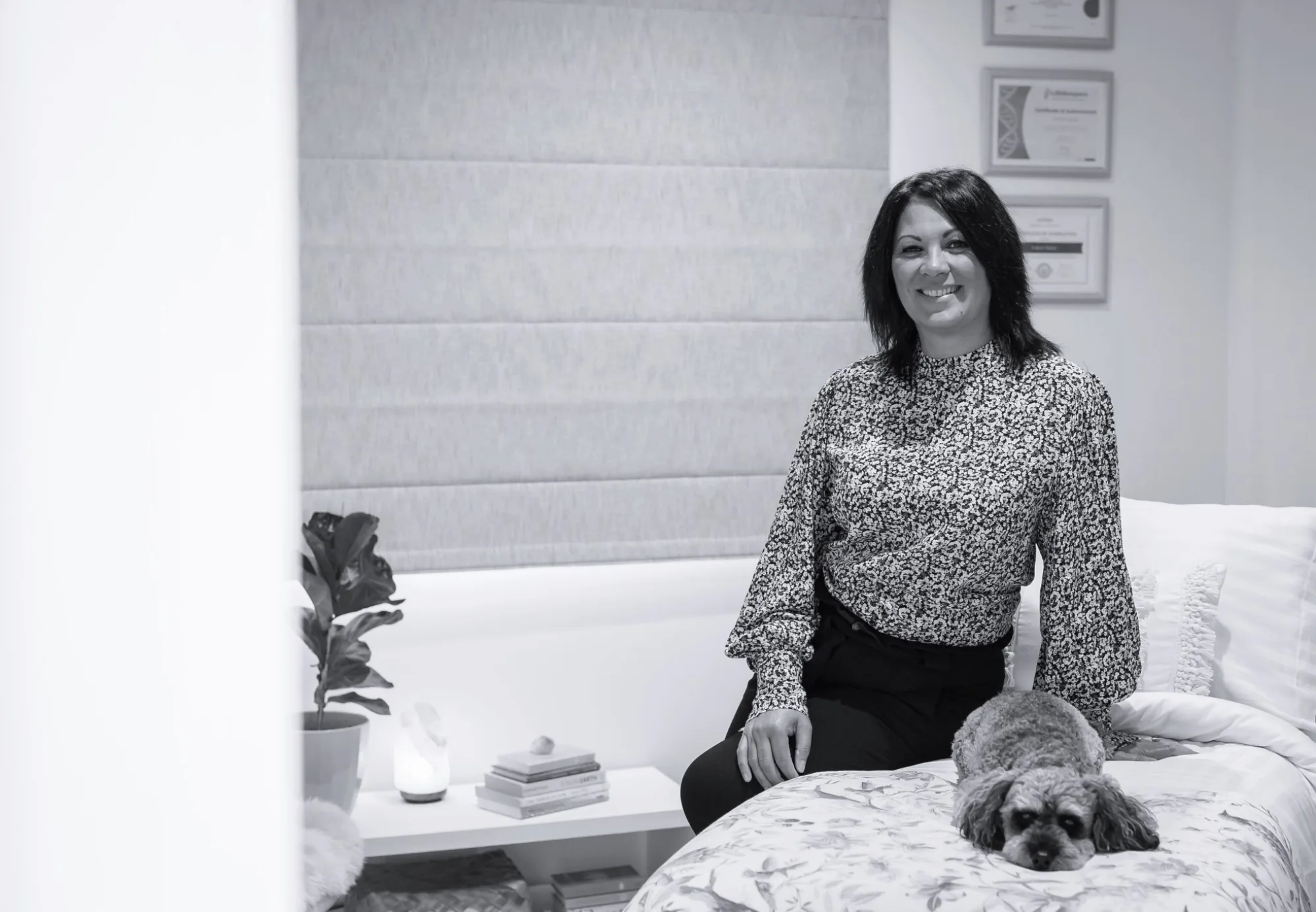 Sharon Gibson smiling in her Whangārei practice room, with her dog Buddy resting beside her