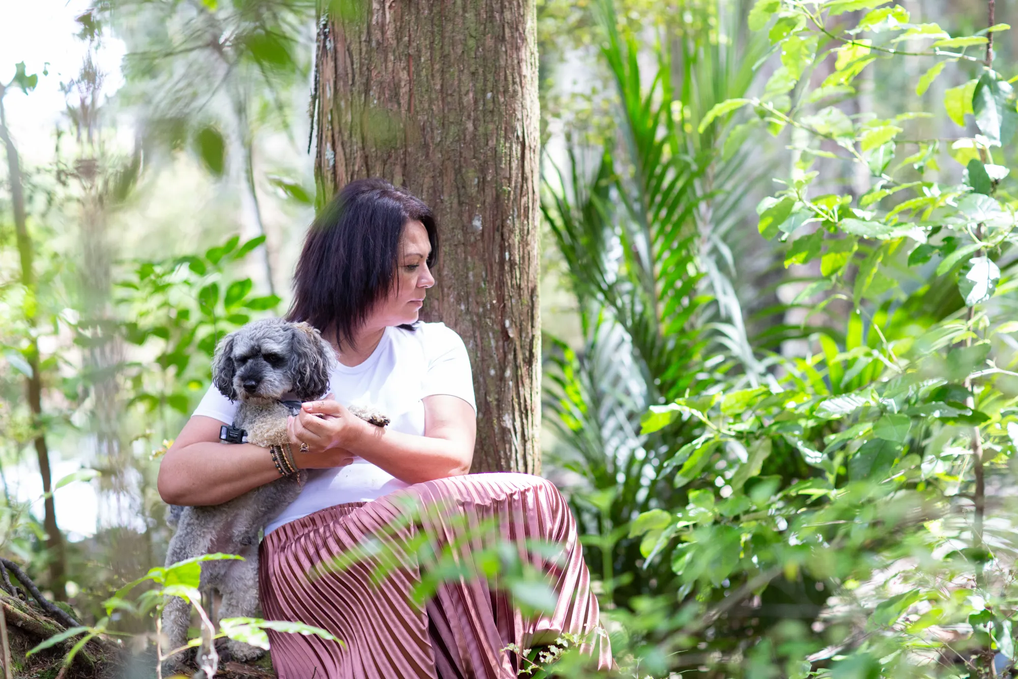 Sharon Gibson sitting with her dog in native bush in Te Tai Tokerau